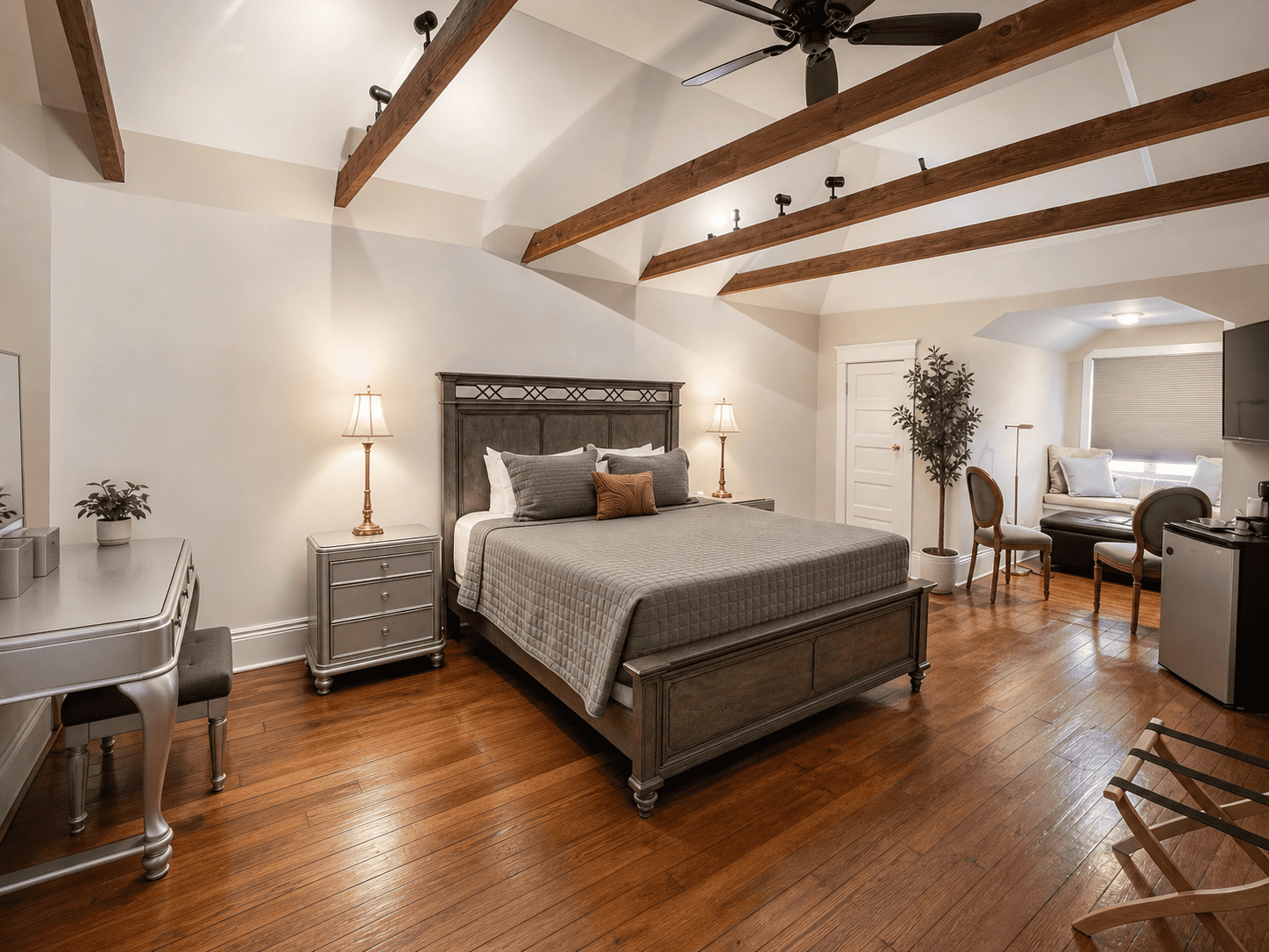 The Audubon Room — king bed with trellis headboard, vaulted ceiling with exposed beams, vanity, and sitting area