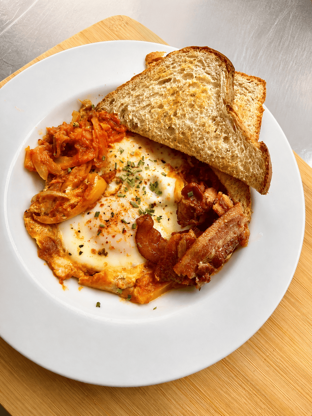 Eggs with bacon, toasted sourdough, and sautéed peppers served fresh from the kitchen