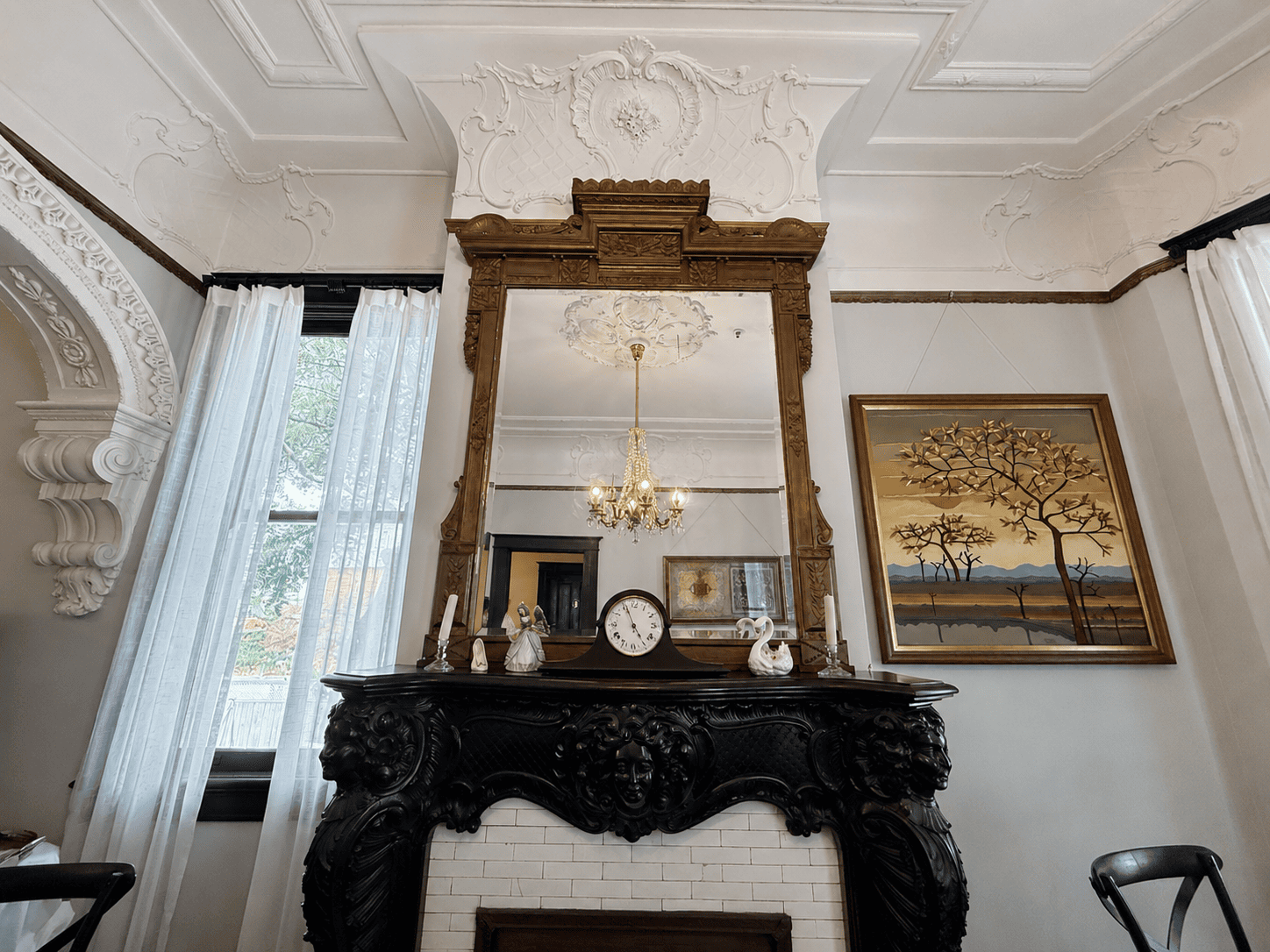 Ornate carved fireplace mantel with gilded mirror and crystal chandelier reflection in a Canal Street Inn parlor