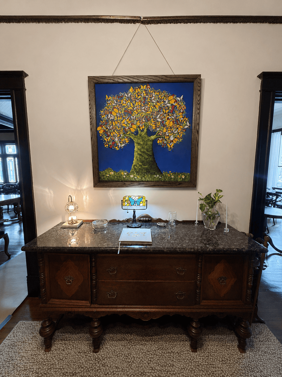 Antique carved wood sideboard with stained glass lamp and butterfly tree artwork in Canal Street Inn hallway