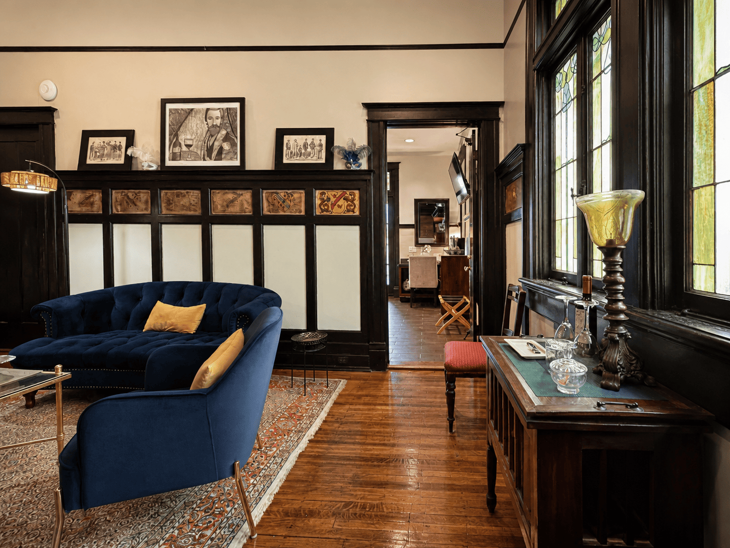 Endymion Suite — sitting area with navy velvet seating, dark wood wainscoting, and stained-glass windows