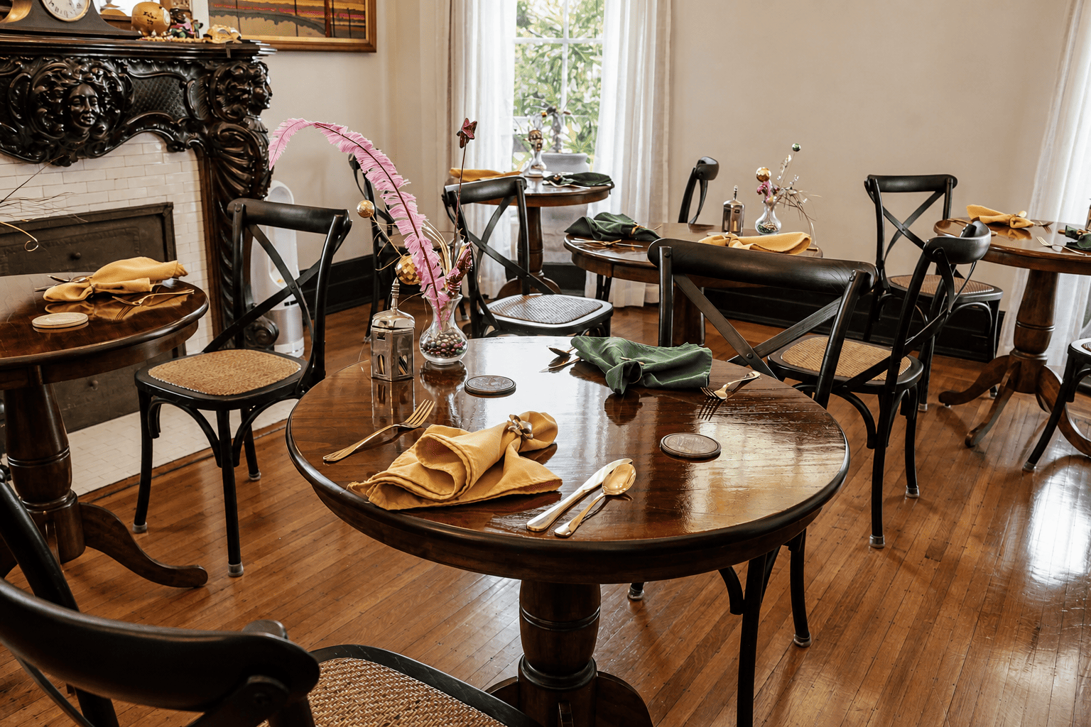 Formal dining room at Canal Street Inn with round tables, cane chairs, and ornate fireplace