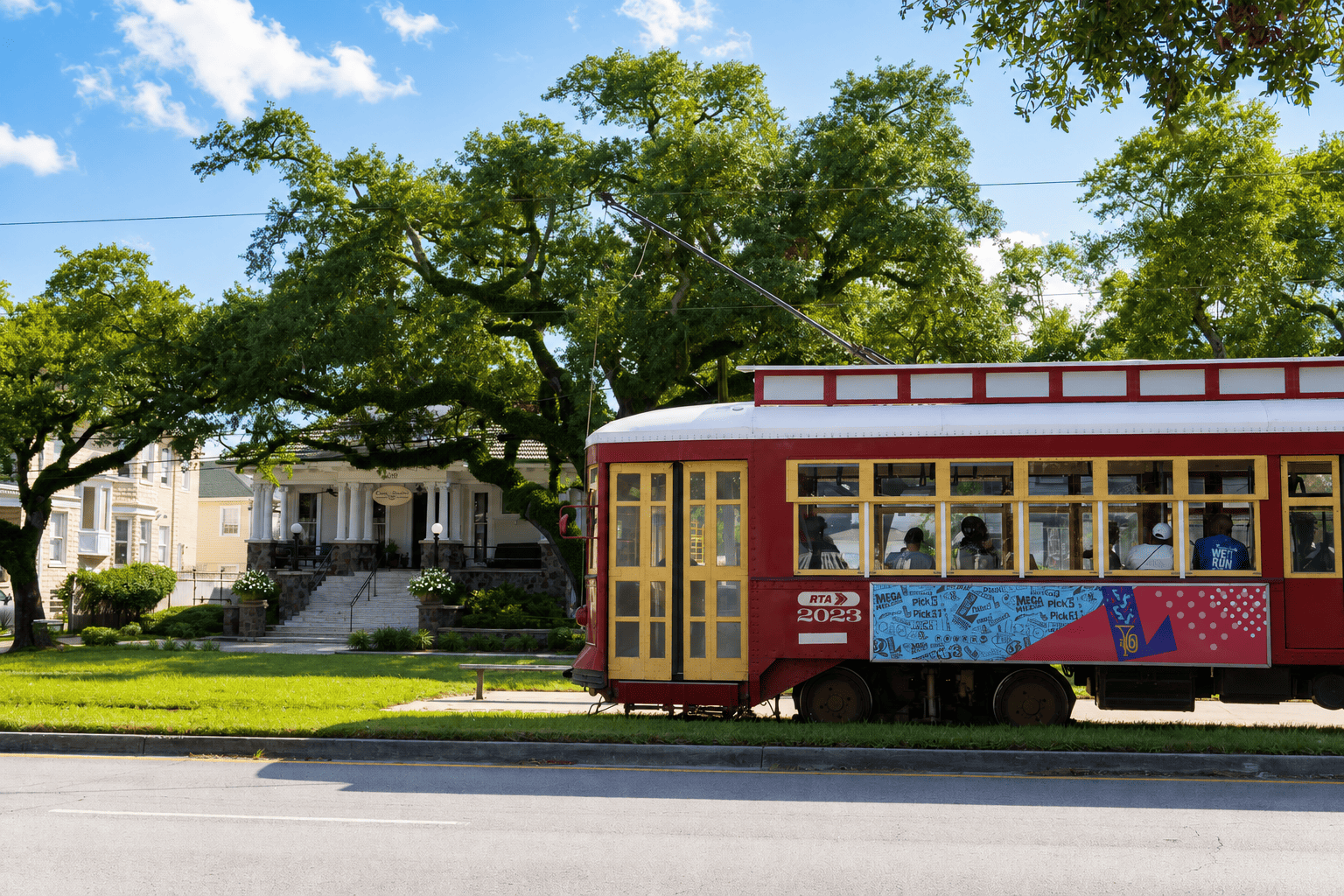 Red New Orleans RTA streetcar passing Canal Street Inn under a clear blue sky