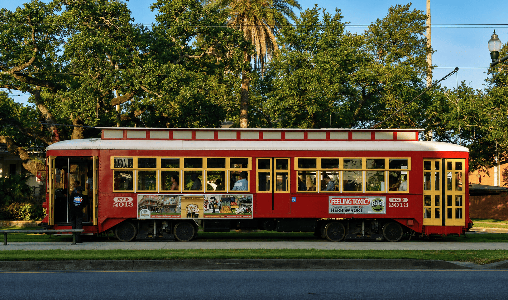 Red Canal Street streetcar stopped beneath live oaks in Mid-City New Orleans