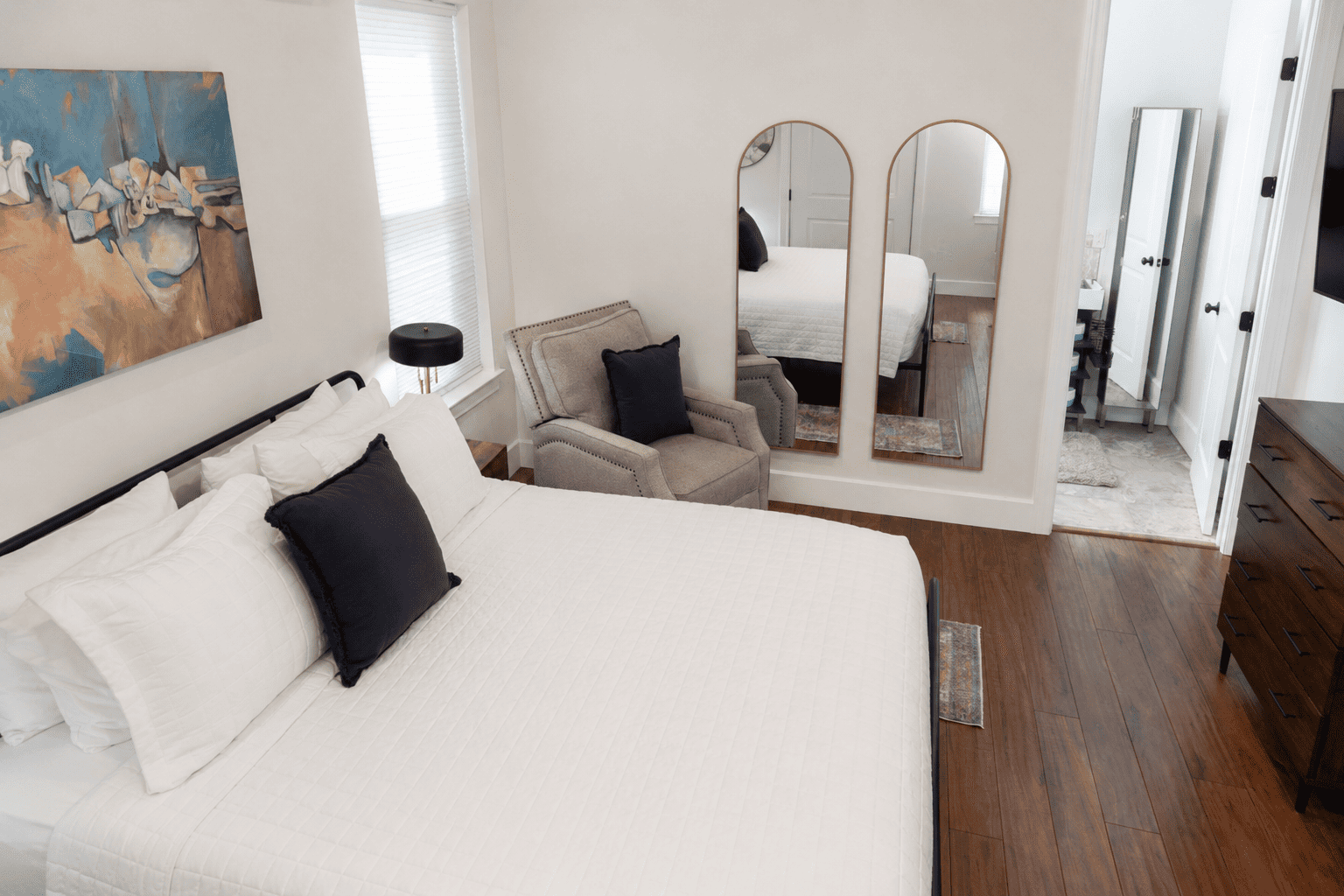Petite Garden Suite — king bedroom with arched mirrors, armchair, and dresser