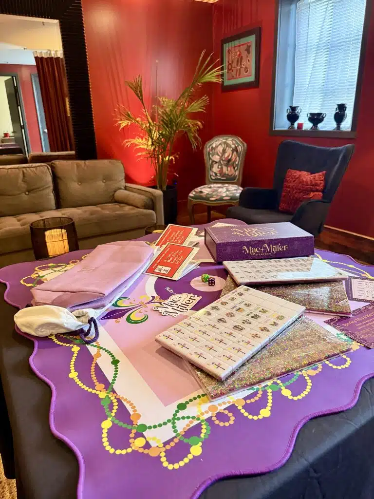 Mahjong tiles, racks, and Mardi Gras beads laid out for play at Canal Street Inn