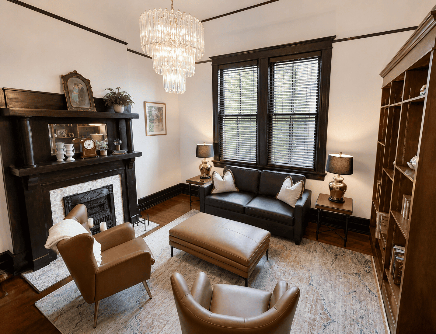 The Prytania Suite — sitting room with leather chairs, crystal chandelier, and mahogany fireplace