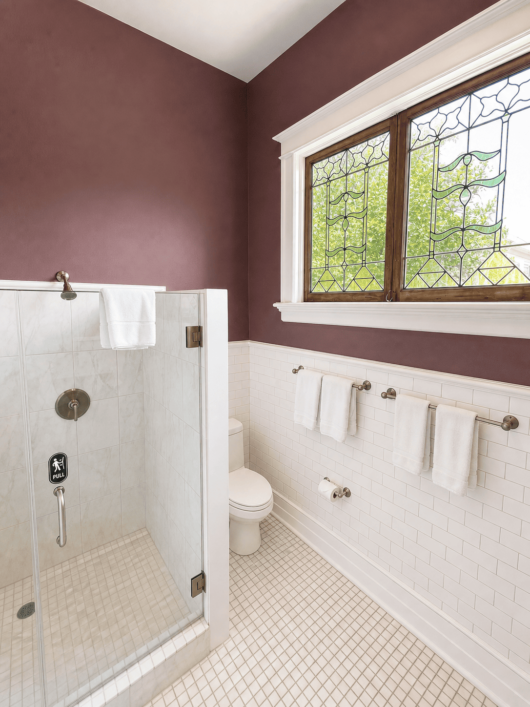 The Prytania Suite — walk-in shower, stained-glass window, and plum upper walls with subway tile