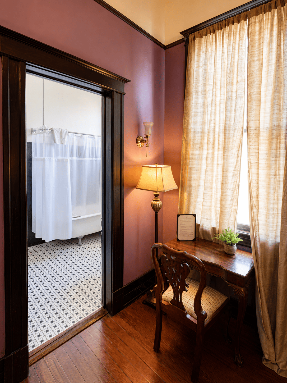 The Royal Street Room — writing desk by the window looking through to the claw-foot tub bathroom