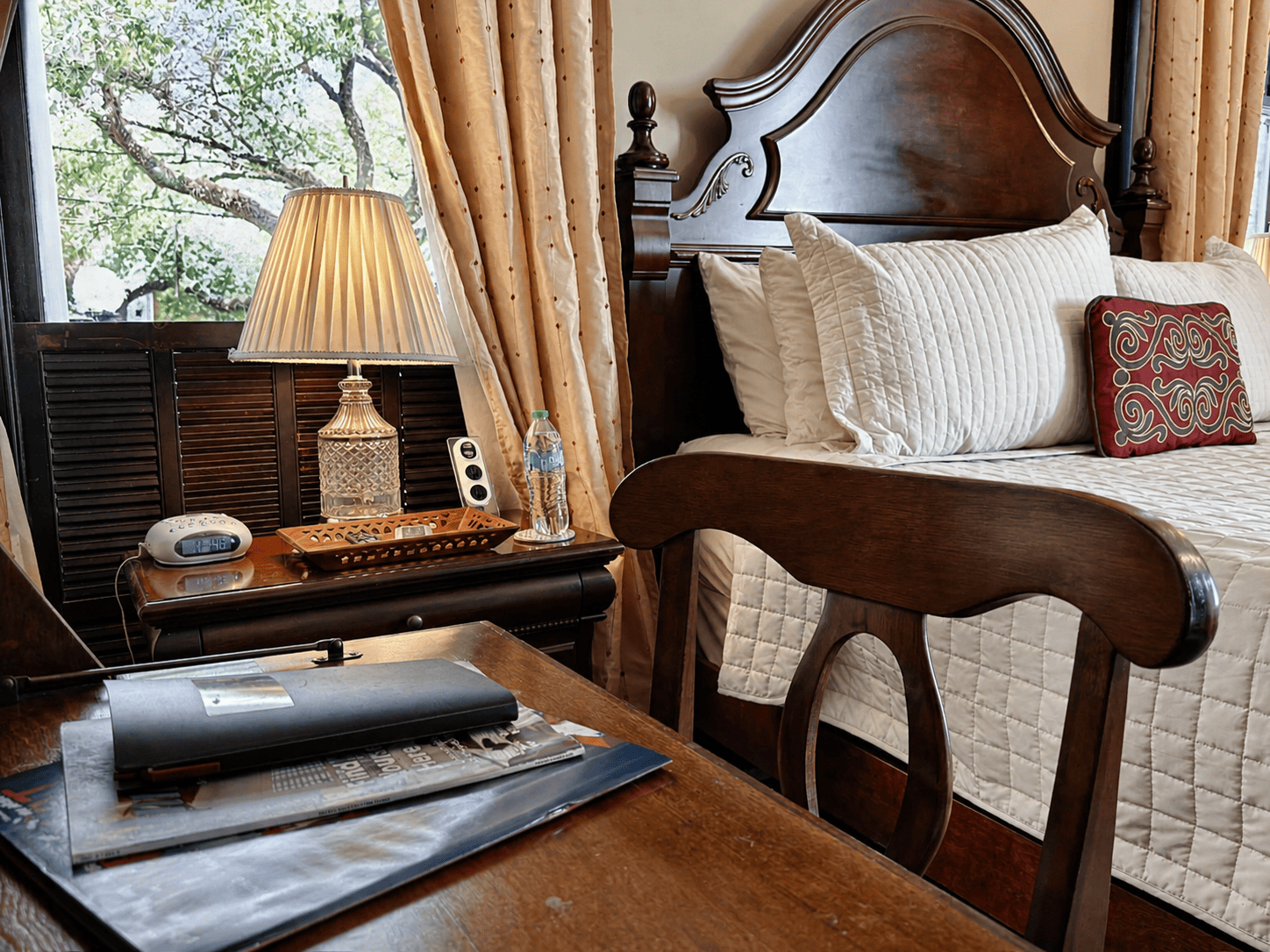 The Street Car Room — carved mahogany headboard, bedside lamp, and Canal Street window