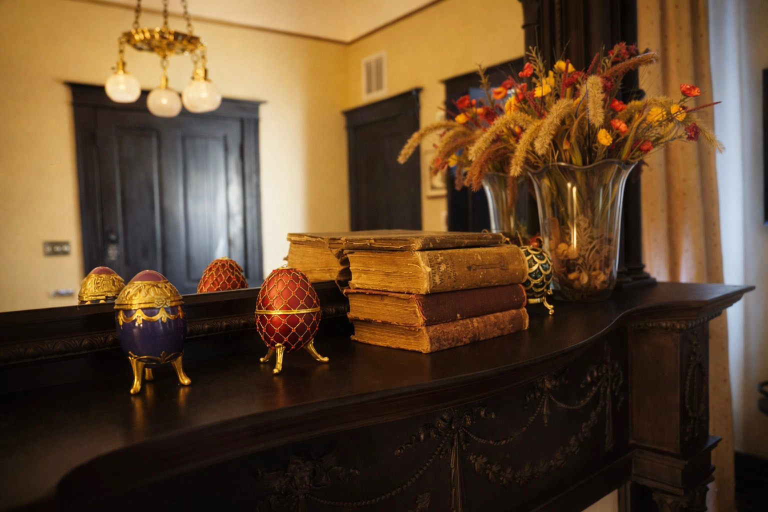 The Street Car Room — neo-Classical mahogany mantelpiece with decorative eggs, antique books, and dried flowers