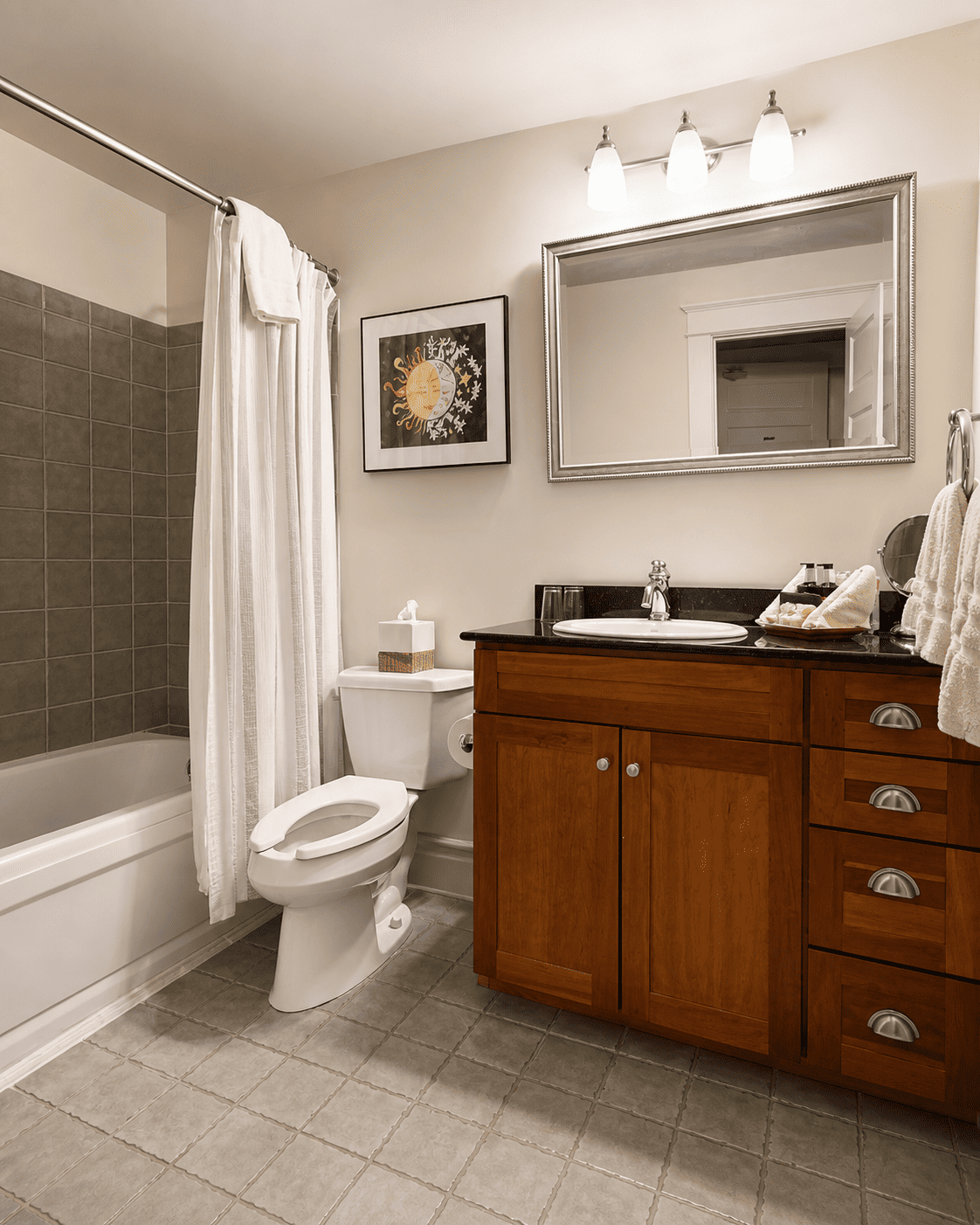The Canal Street Room — bathroom with tub and shower, wooden vanity, granite countertop, and sun-and-moon artwork