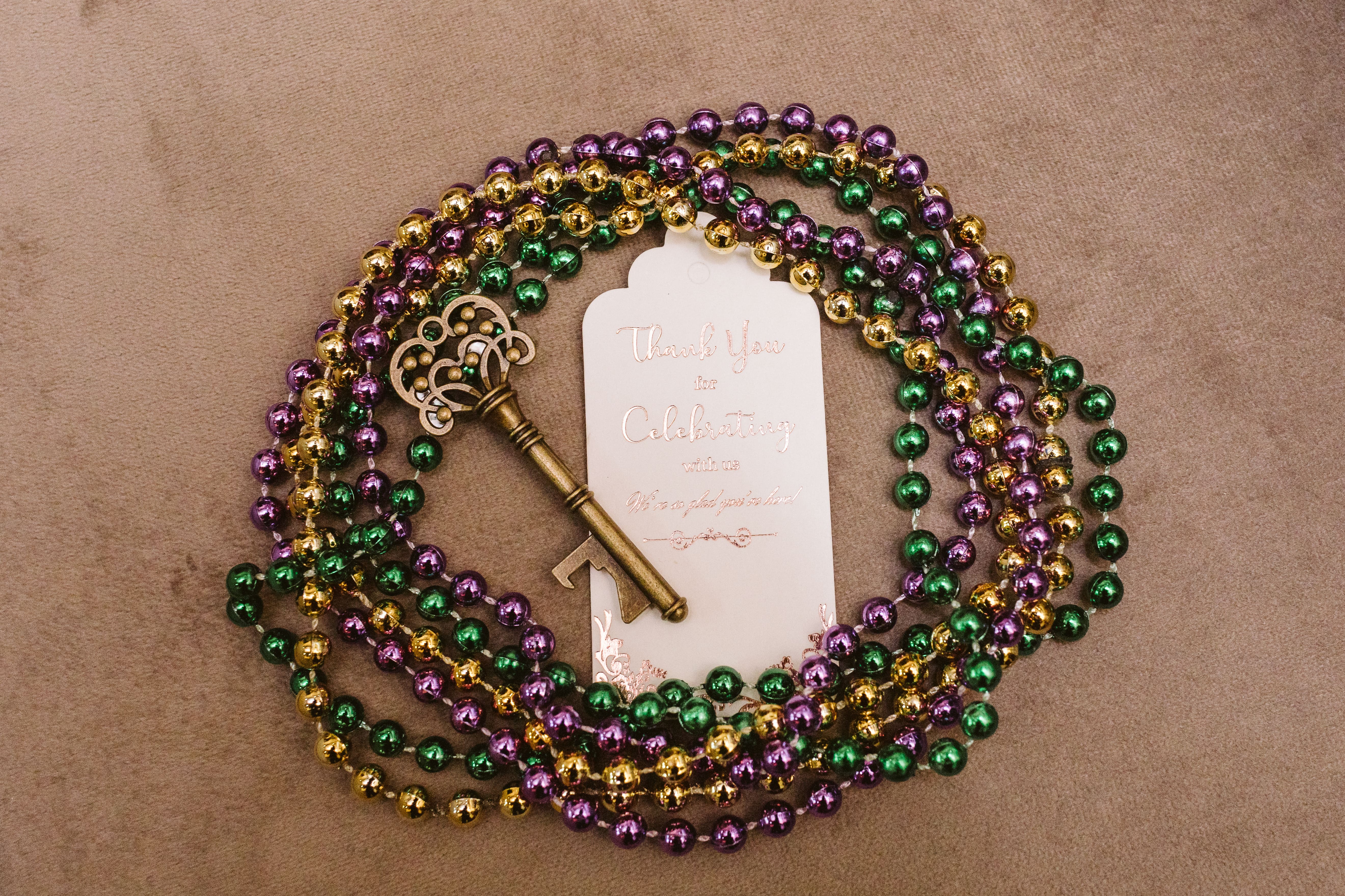 New Orleans wedding favor with Mardi Gras beads and an ornate brass key on a thank-you tag